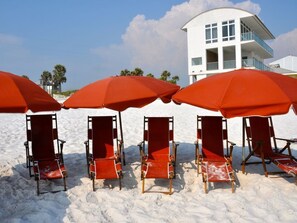 Beach chairs and umbrellas on a sandy beach with a white building in the background. - *PRIVATE BEACH*    *PRIVATE POOL*    *ELEVATOR*    *6 BEACH BIKES* (Panama City)