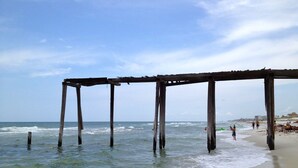 A beach with wooden structures extending into the water, a sandy shore, and a clear sky. - *PRIVATE BEACH*    *PRIVATE POOL*    *ELEVATOR*    *6 BEACH BIKES* (Panama City)