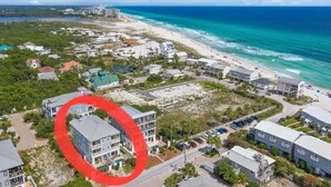 An aerial view of a coastal town with beachfront properties, a marina, and a large building circled in red. - *PRIVATE BEACH*    *PRIVATE POOL*    *ELEVATOR*    *6 BEACH BIKES* (Panama City)