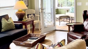 Een woonkamer met een bank, fauteuils, een salontafel en een eethoek met een tafel en stoelen.