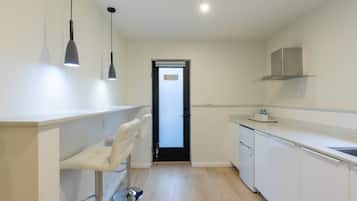 Une cuisine moderne avec des meubles blancs, une porte noire et des luminaires suspendus.