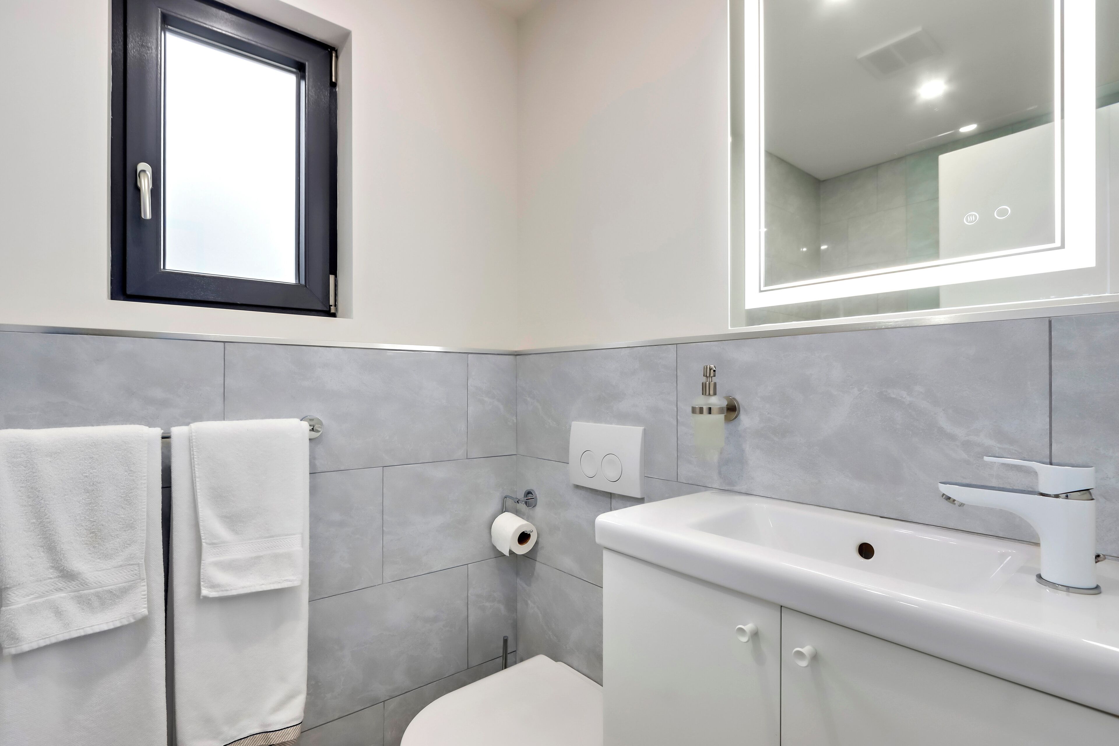 Un baño moderno con inodoro, lavamanos y toallero.