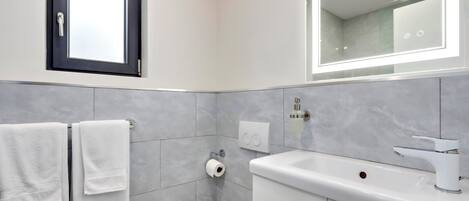 Un baño moderno con inodoro, lavamanos y toallero.