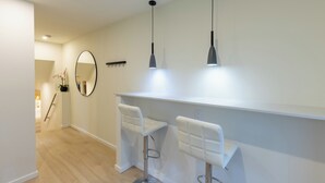 Une cuisine moderne avec des tabourets de bar blancs, des luminaires suspendus et un grand miroir.
