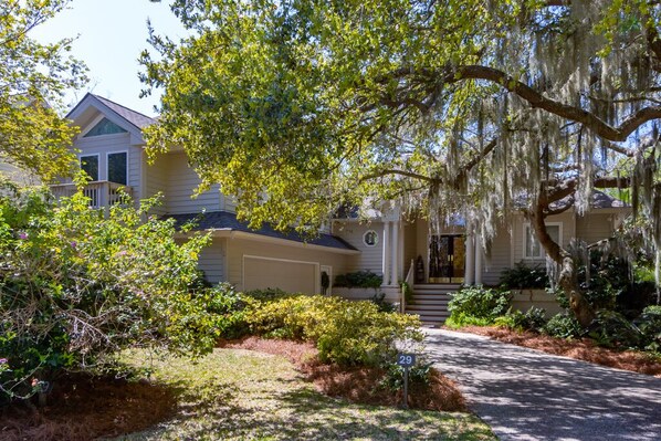 A two-story house with a front porch, surrounded by lush greenery and a well-maintained lawn.