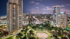 A high-rise residential building with multiple floors, surrounded by a landscaped park area with pathways and trees. - Luxury 5-Bedroom Oceanfront Penthouse with Private Pool (Bat Yam)