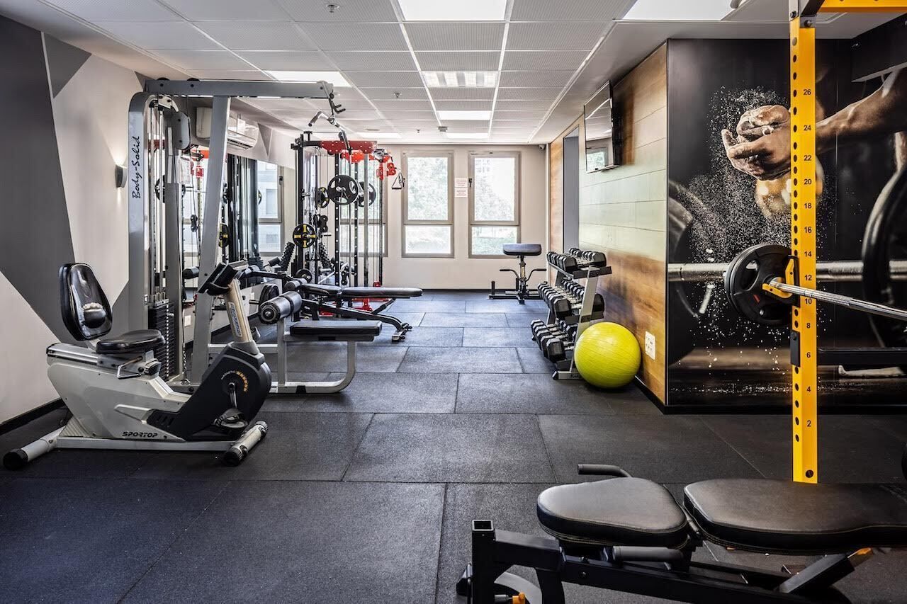 Et fitnesscenter med træningsmaskiner, styrkeudstyr og en yogabold.