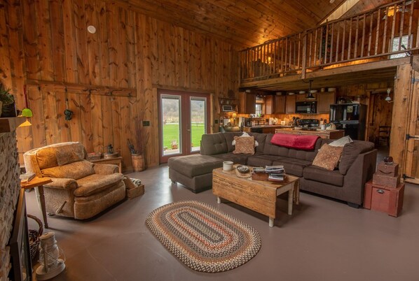 A rustic cabin interior with a cozy living area featuring a sofa, armchair, and coffee table.