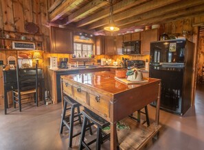 A rustic kitchen with wooden cabinets, a central island, and bar stools.