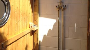 Een houten hut met een douche en een klein plankje.