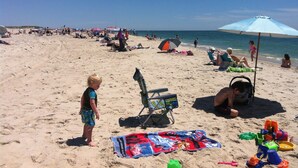 Een strand met mensen, parasols en strandstoelen.
