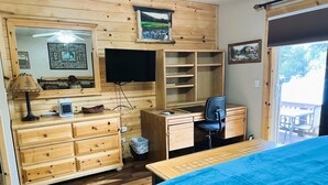 Una habitación de madera con cama, escritorio, silla y televisor.