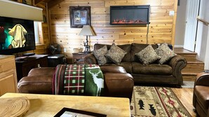 Una sala de estar acogedora con chimenea, sofás de cuero, un televisor y detalles de madera.