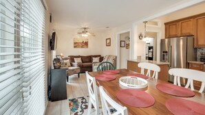 A modern kitchen with a wooden countertop, stainless steel appliances, and a dining area with a wooden table and white chairs. - Gwinnett St Row: Historic 3 BR 2BA - Balcony - Free St Parking - Near Forsyth Pk (Savannah)