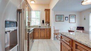 A modern kitchen with wooden cabinets, a granite countertop, and a built-in dishwasher. - Gwinnett St Row: Historic 3 BR 2BA - Balcony - Free St Parking - Near Forsyth Pk (Savannah)
