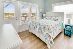 A bedroom with a bed, a nightstand, a window with a view, and a door. - Oceanfront Dog Friendly Home with Pool, Hot Tub, EV Charger, and Home Theater (Salvo)