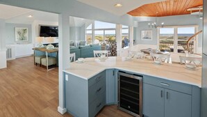 A modern kitchen with a central island, built-in appliances, and large windows offering views of the outdoors. - Oceanfront Dog Friendly Home with Pool, Hot Tub, EV Charger, and Home Theater (Salvo)
