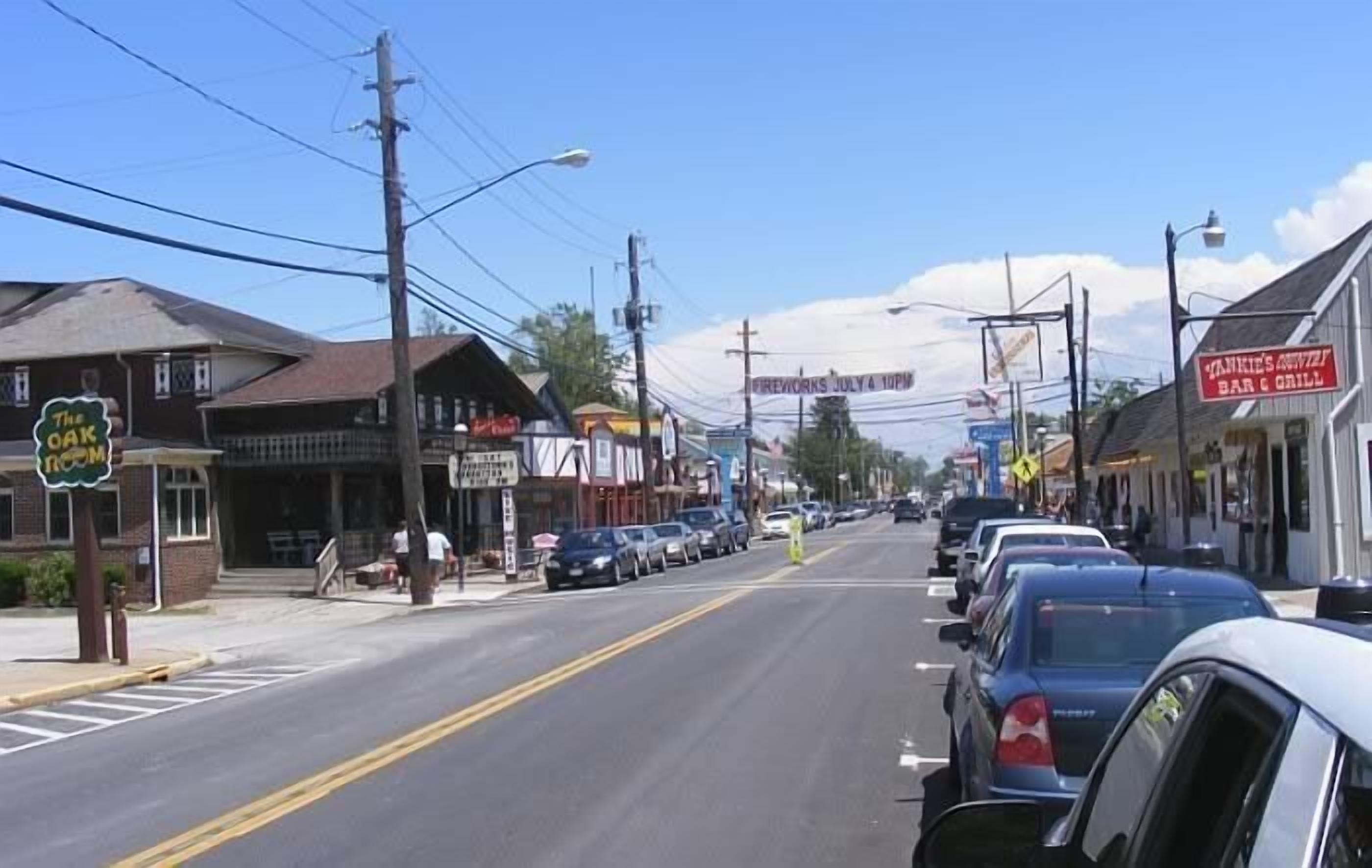 A street view with parked cars, buildings, and a sign for 'The Oak Room'.
