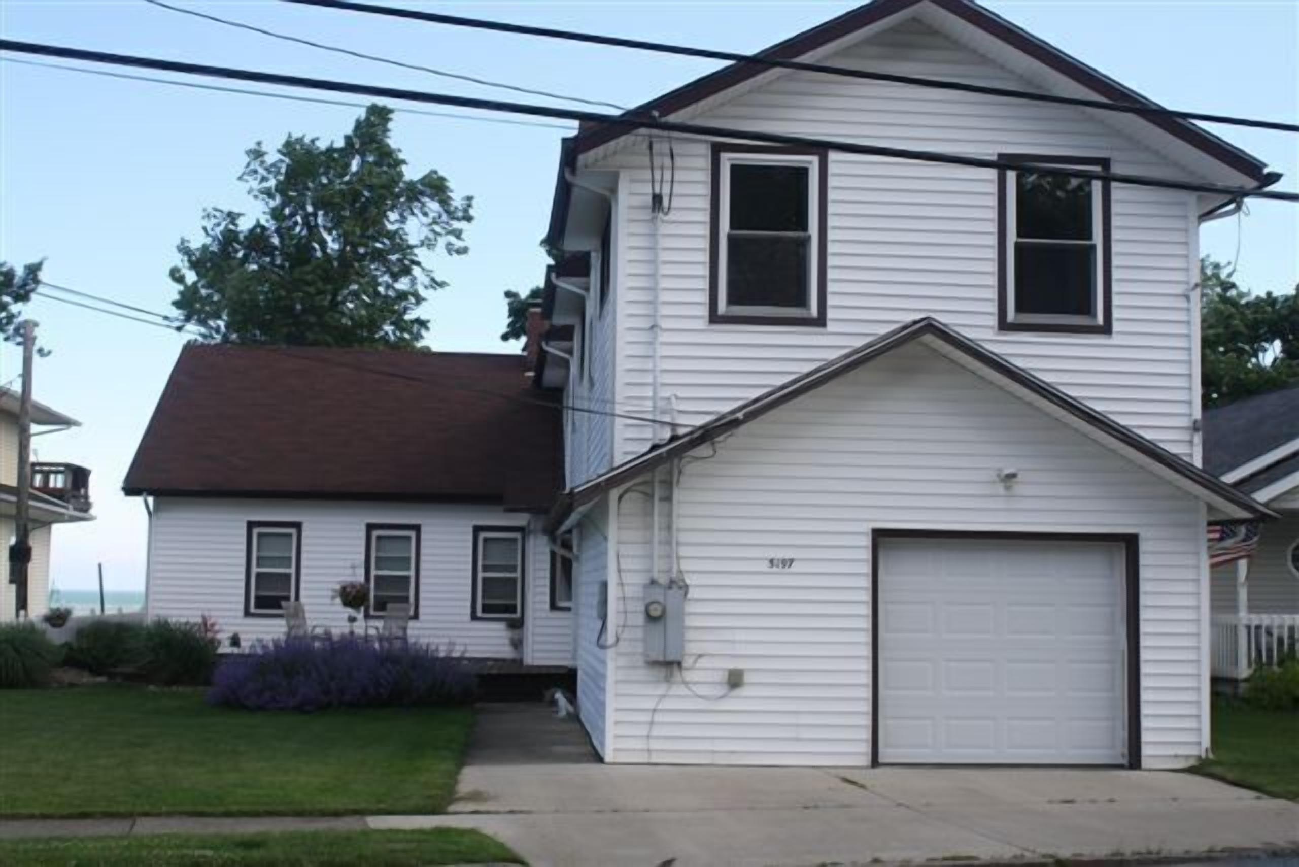 A two-story house with a garage, a visible number '5197', and a small front yard with a lawn and some plants.