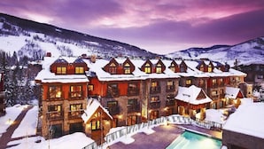 Eine mehrstöckige Lodge mit Poolbereich, umgeben von schneebedeckten Bergen.