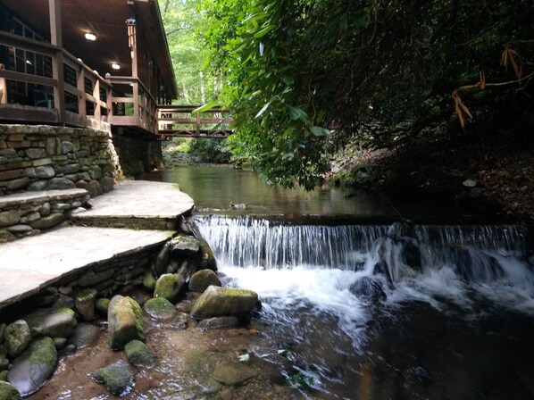 Una escala de pedra que condueix a una terrassa de fusta amb vista a una petita cascada.