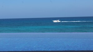 A pool with a view of the ocean and a boat in the distance. - Beautiful Oceanfront Mexican Villa with Infinity Pool, and Spectacular View (Isla Mujeres)