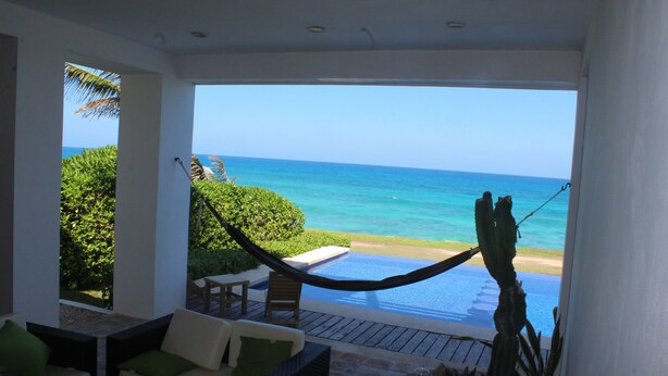 A room with a view of the ocean, a hammock, and a pool. - Beautiful Oceanfront Mexican Villa with Infinity Pool, and Spectacular View (Isla Mujeres)