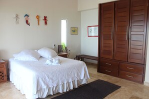 A bedroom with a large bed, a wardrobe, and wall decorations.