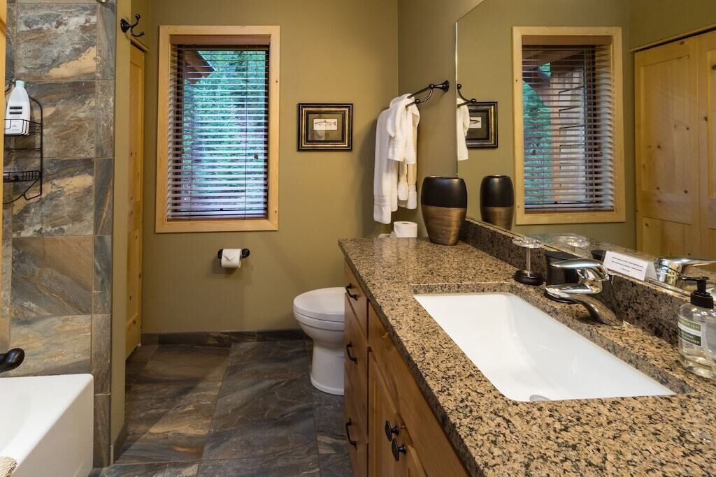 Ein Badezimmer mit Granitwaschtisch, einem weißen Waschbecken, einer Toilette und einer Duschkabine.