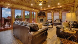 A spacious living room with a leather sofa, a fireplace, and a television. - A Heavenly View Too ~ 6 BR w/ Indoor Pool ~ Sleeps 28 ~ Incredible Views! (Sevierville)
