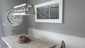Uma sala de jantar com uma mesa de madeira, um cesto de pão e um lustre.