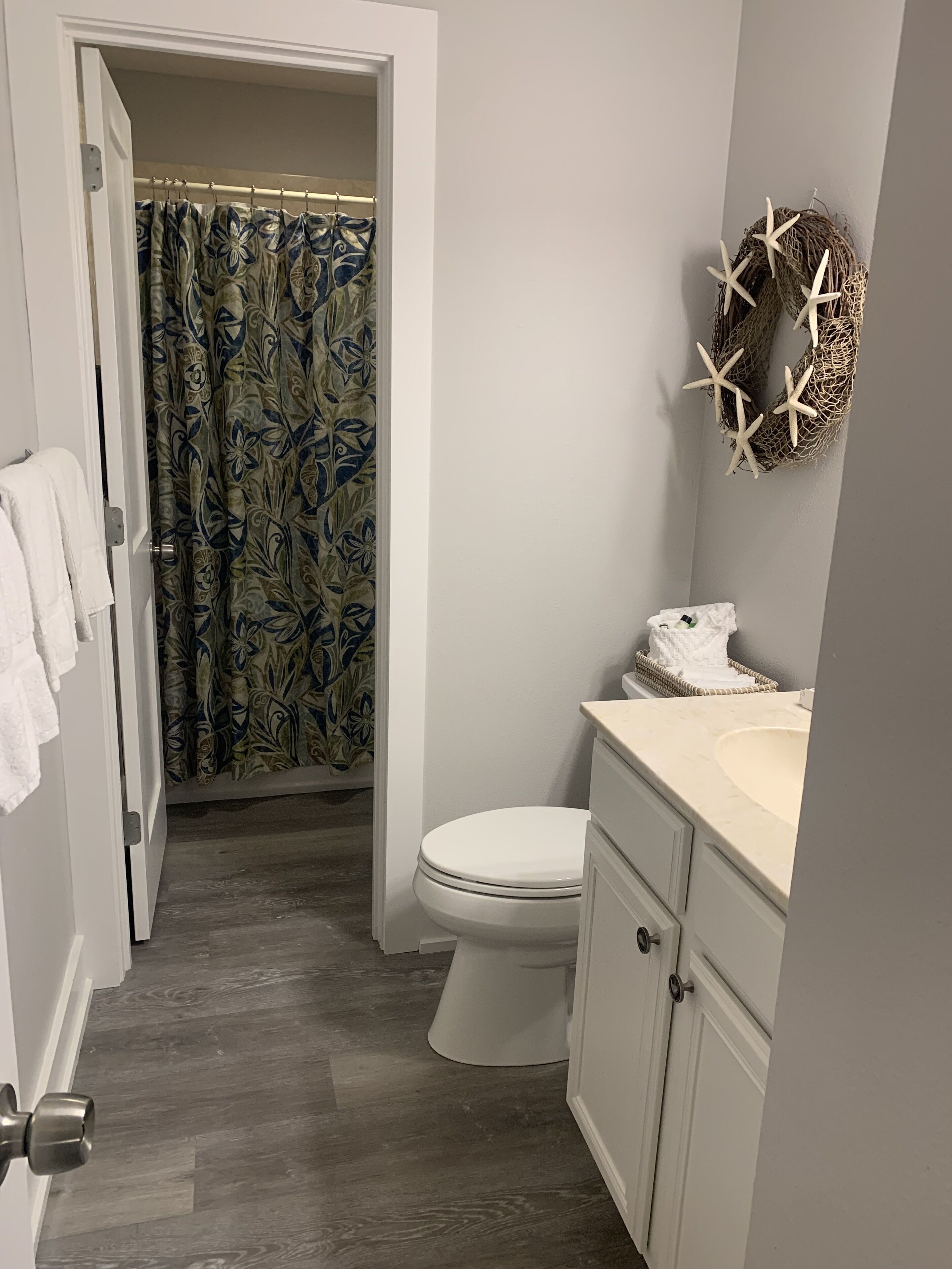 Un baño con inodoro, lavamanos, cortina de ducha y un adorno decorativo.