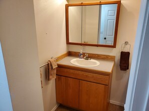 A bathroom with a wooden vanity, a sink, a mirror, and a towel rack.