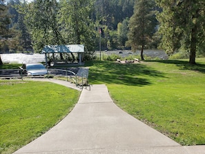 Stroll along the lakeside walkway to a serene picnic area surrounded by lush greenery and trees.