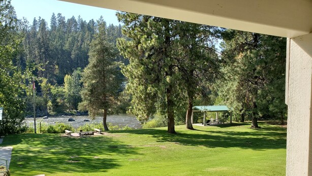 A well-maintained lawn with a picnic area and a gazebo overlooking a river.