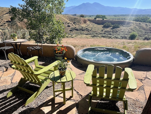 Outdoor seating with chairs and a hot tub, surrounded by a patio area with a view of a mountainous landscape.