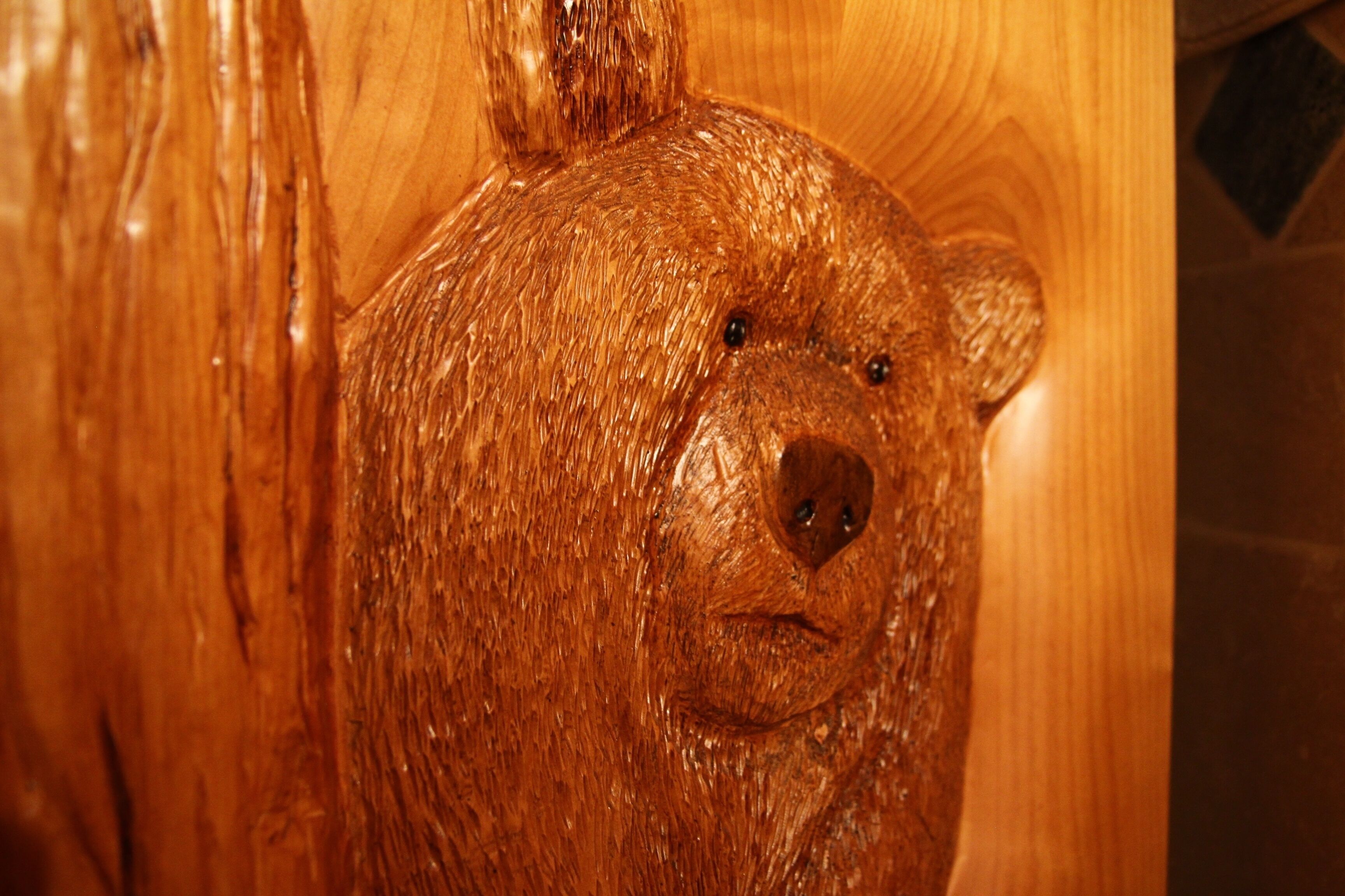 A wooden sculpture of a bear's head carved into a wooden surface.