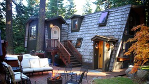 A cozy outdoor patio with a fire pit, seating area, and a wooden staircase leading to a loft bedroom. - Cabin & Spa - Luxurious & Private 2 blocks from the lake and conservancy  (Tahoe City)