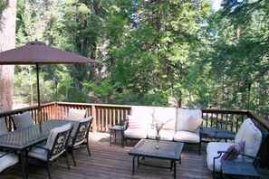 An outdoor deck with a table and chairs, a sofa, and an umbrella.