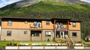Un edificio de madera de dos pisos con un balcón, una escalera y vistas a la montaña.