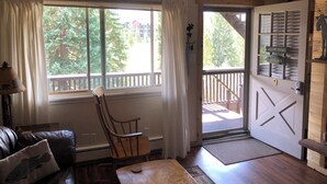 A cozy room with a wooden chair, a small table, and a window with curtains. - A cozy non-smoking condo on the Fraser River in downtown Winter Park. (Winter Park)