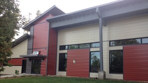 A modern building with a red and beige facade, large windows, and a well-maintained lawn. - A cozy non-smoking condo on the Fraser River in downtown Winter Park. (Winter Park)