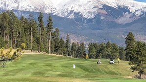 A golf course with a flag, trees, and a mountain in the background. - A cozy non-smoking condo on the Fraser River in downtown Winter Park. (Winter Park)