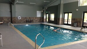 An indoor swimming pool with a diving board, tiled walls, and a clear view of the pool area. - A cozy non-smoking condo on the Fraser River in downtown Winter Park. (Winter Park)
