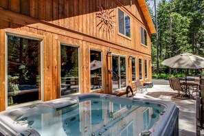 A wooden cabin with a hot tub and outdoor seating area. - Theater, Hot Tub & River Access. This home was built for big groups! (Leavenworth)