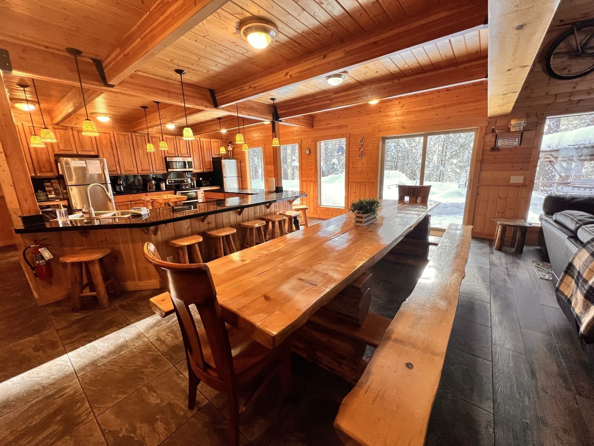 Une cuisine spacieuse avec un grand îlot central en bois, des tabourets de bar et une grande table à manger.