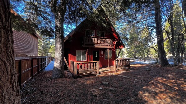 Une cabane dotée d’une terrasse en bois, d’un porche et d’un espace clôturé.