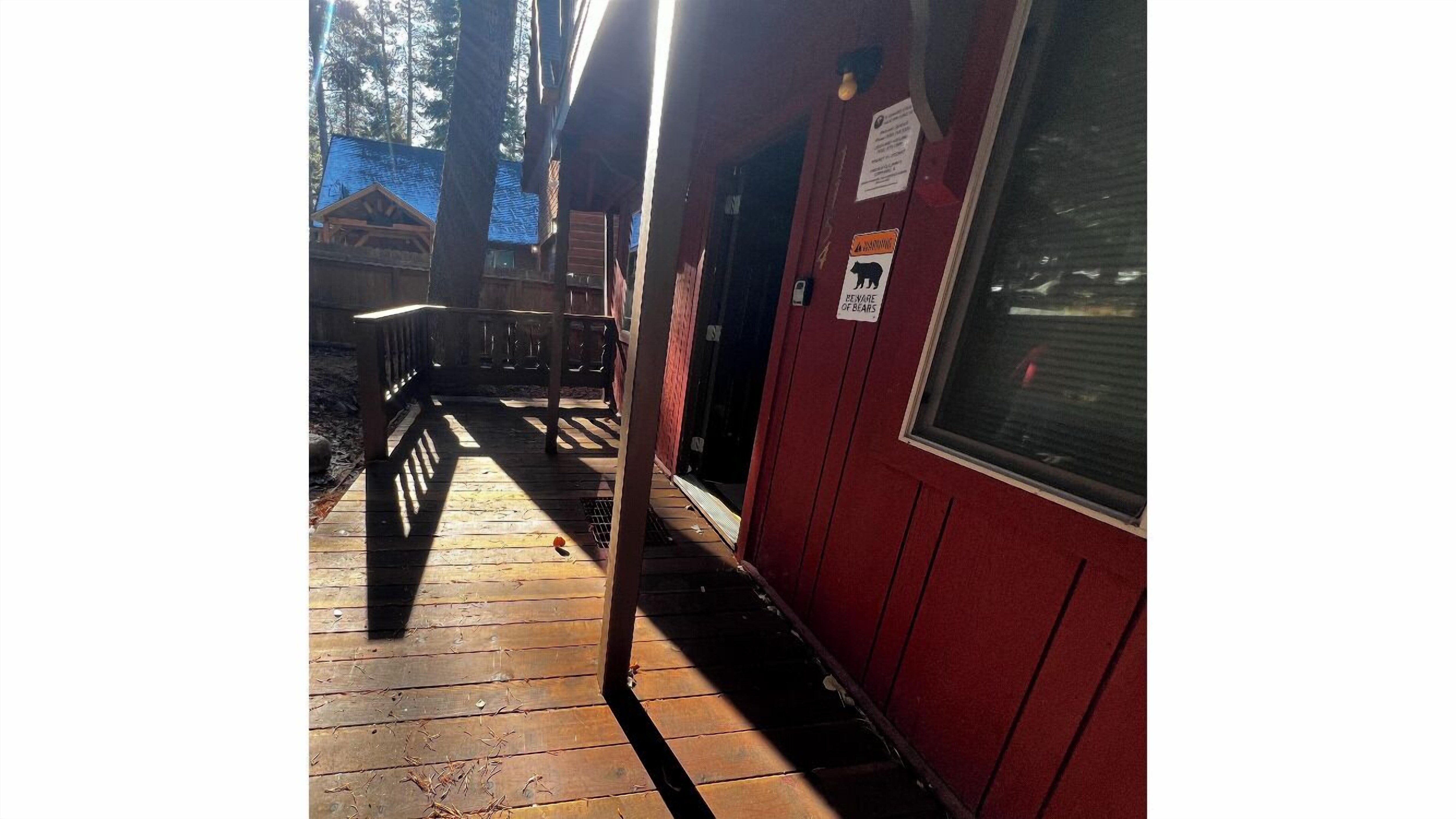Eine Holzterrasse führt zu einem Gebäude mit roter Fassade und einem Schild mit Warnung vor Bären.
