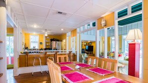 A bright kitchen with a wooden table set for dining, a refrigerator, and a TV in the background. - 'Roger's Lighthouse' in the Heart of Seaside. Bikes included.  (seaside)