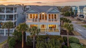 A two-story beachfront house with a balcony, surrounded by palm trees and well-maintained landscaping. - Ask for Discounts!! Palm Manor by Exclusive Properties  Pool, Elevator, Views (Isle of Palms)